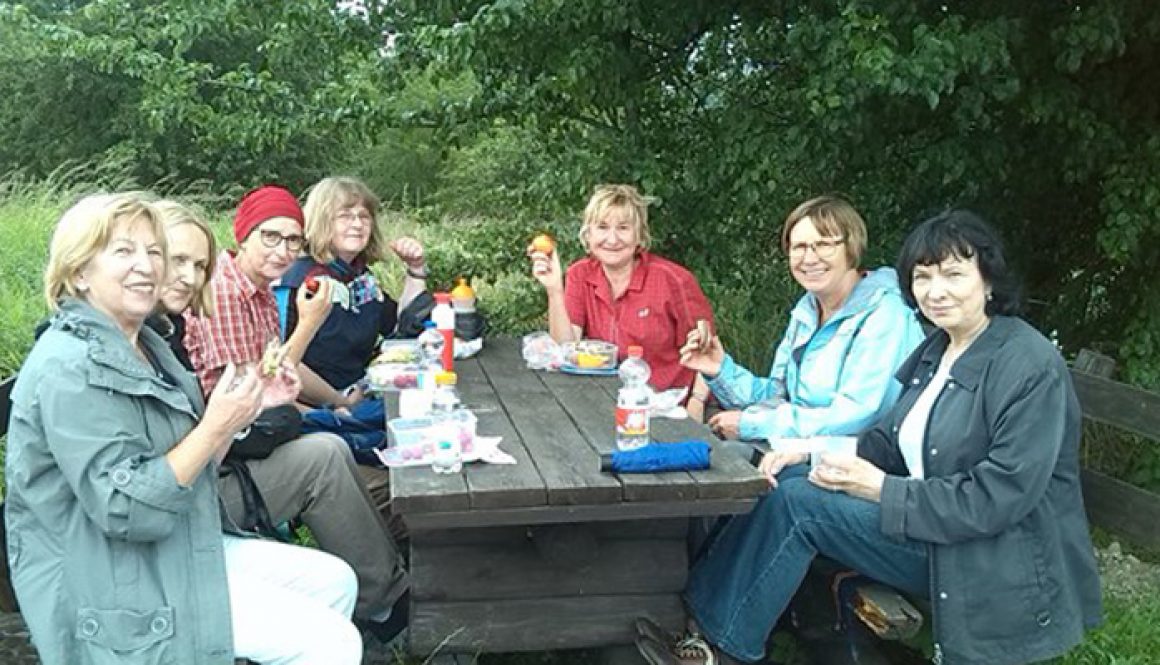 7 Frauen sitzen in der Runde an einem Picknick-Tisch und lächeln in die Kamera © FRIEDA