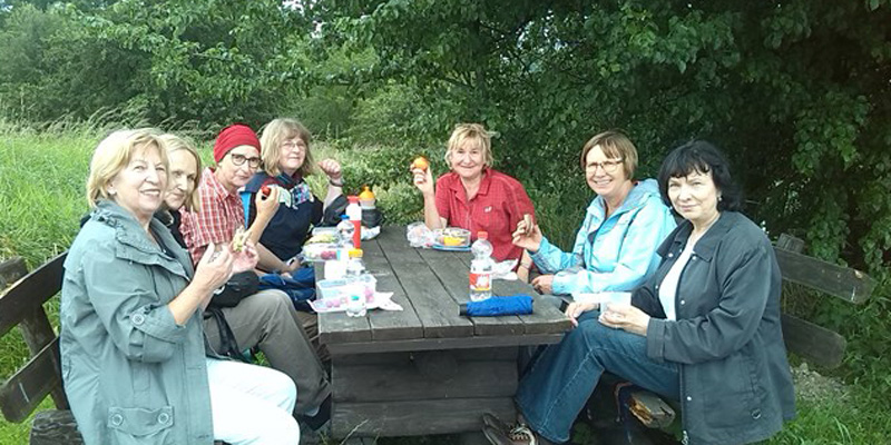 7 Frauen sitzen in der Runde an einem Picknick-Tisch und lächeln in die Kamera © FRIEDA